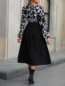 Detail view of the back of a black and white cow print long sleeve midi dress