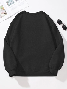 Flat lay of a plain black crewneck sweatshirt with ribbed cuffs and magazine decoration