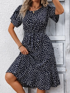 Detail of navy blue summer dress with white teardrop print and elegant ruffled hemline