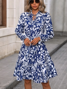 Detail of elegant blue and white floral dress with ruffle collar and tie-neck design
