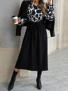 Detail of elegant contrast dress featuring cow print bodice and belted waist design