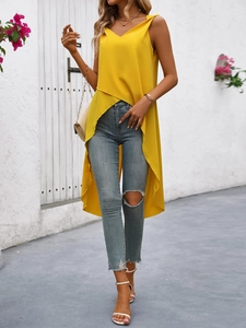 Dettaglio del top giallo con spalle scoperte, orlo asimmetrico e jeans in denim strappati