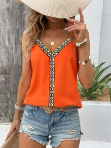 Close-up of ethnic embroidery and deep V-neckline on orange summer camisole top