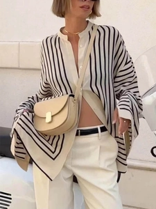 Detail van een oversized gestreept damesshirt met beige pantalon met hoge taille