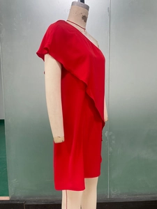 Detail of red one-shoulder dress showing ruffled layers and vibrant textile texture