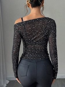 Back view of a sheer black long-sleeve mesh top with white polka dots and cold shoulder