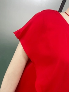 Detailed close-up of red ruffled sleeve edges and lightweight fabric on female dress