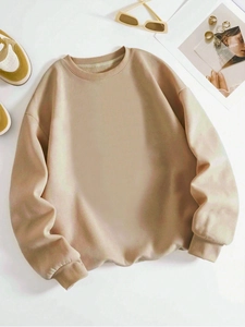 Flat lay of khaki crewneck sweatshirt styled with sneakers and sunglasses