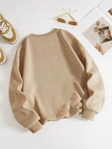 Flat lay detail of khaki crewneck sweatshirt with ribbed cuffs and lifestyle props