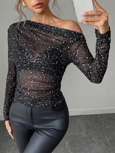 Detail of sheer black mesh top with white splatter print and asymmetrical off-shoulder cut