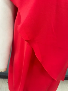 Detail of red ruffled off-shoulder dress showing smooth silky fabric and quality stitching