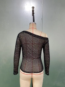 Detail of black mesh top with glitter dots and asymmetrical off-shoulder neckline
