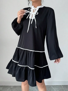 Detail of black long-sleeved dress featuring contrast white trim and double tiered ruffle hem