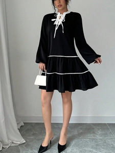 Detail of the black tiered dress with white ribbon necktie and lantern long sleeves