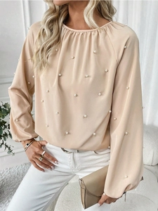 Detailed view of elegant light apricot long-sleeved shirt featuring white pearl embellishments