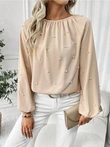 Detailed view of apricot blouse featuring delicate white pearl beadwork and pleated collar