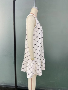 Detail of white sleeveless dress featuring black bow grid print and ruffled hemline