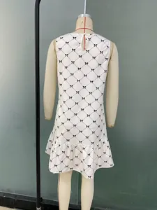 Detail of sleeveless plaid dress featuring bow prints and a ruffled hemline on woven fabric