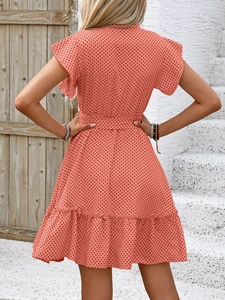 Détail du dos d'une robe trapèze orange à pois avec des manches à volants et ceinture