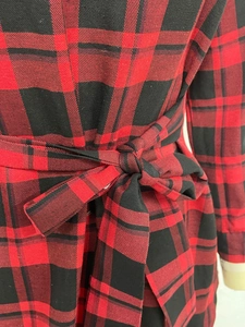 Detail of red and black plaid dress waist featuring a tied bow and twill fabric texture