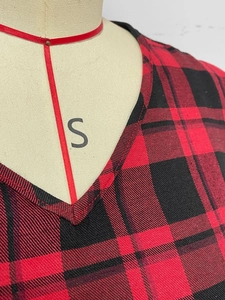Detail of V-neckline and red black tartan pattern on a long sleeve elegant dress