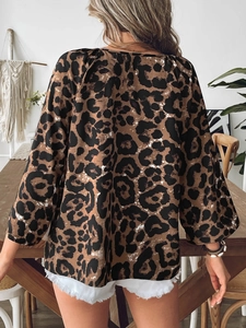 Rear view of model wearing leopard print blouse with subtle lantern sleeves in home setting