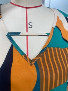 Dettaglio dello scollo a V del vestito con stampa geometrica e sottile cinturino decorativo