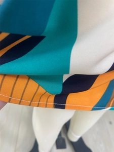 Dettaglio dell'abito patchwork geometrico multicolore con cuciture sull'orlo