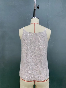 Close-up detail of white sequin camisole top featuring reflective circular sequins for parties
