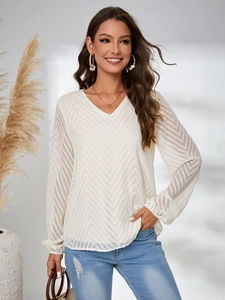 Détail de la blouse blanche à col en V montrant la texture ondulée et la coupe fluide