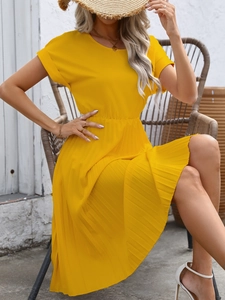 Detail view of a bright yellow pleated summer dress with short sleeves and waist tie