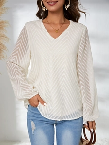 Vue détaillée de la blouse blanche à col en V avec motif texturé et manches lanternes