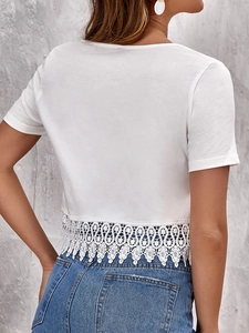 Detail of white short sleeve top with delicate crochet lace hem and scalloped edges