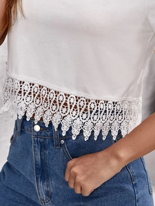 Close-up of white summer top featuring delicate lace crochet hem and scalloped edges