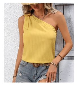 Close-up of yellow one-shoulder top featuring pleated texture and bow detail