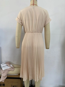 Detail view of the pleated back of a short-sleeved solid-colored pink A-line dress