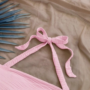 Pink textured halter top with adjustable bow strap detail for elegant summer beach style
