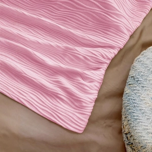 Pink ribbed crop top with strappy tie details on a textured brown background