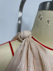Detail aus metallischem Plissee-Stoff mit Knotendesign an der Champagner-Kleid-Schulter