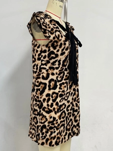 Detail view of the leopard print dress featuring a large black bow tie neckline