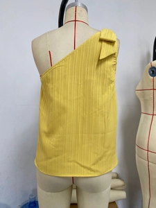 Detail of yellow one-shoulder top showing ribbed fabric and decorative shoulder bow
