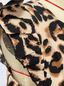 Detailed close-up of leopard print fabric with ruffle edges and precision black stitching