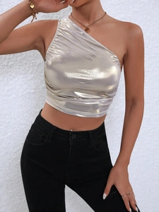 Dettaglio del crop top monospalla oro champagne con finitura metallica e pieghe sottili
