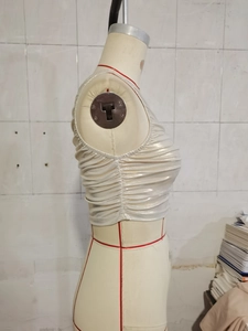 Dettaglio del crop top metallizzato argento con texture a pieghe laterali su manichino