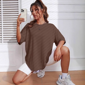 Close-up of oversized brown crew neck t-shirt paired with white shorts and sneakers