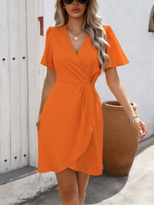 Detail of the bright orange V-neck wrap dress featuring flutter sleeves and waist pleats