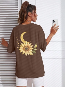 Dettaglio della maglietta marrone oversize con stampa artistica di girasole e luna