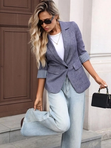 Detail view of stylish grey-blue blazer with striped cuffs and wide-leg jeans