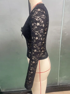 Détail du haut noir à manches longues en dentelle avec motifs floraux ajourés fins