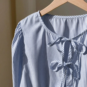 Chemise à rayures bleues et blanches avec nœuds frontaux et manches bouffantes sur cintre